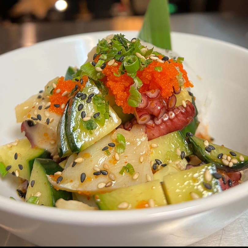 Kenzo Thai & Sushi's octopus salad with cucumber, roe, green onions, and sesame seeds in a white bowl.