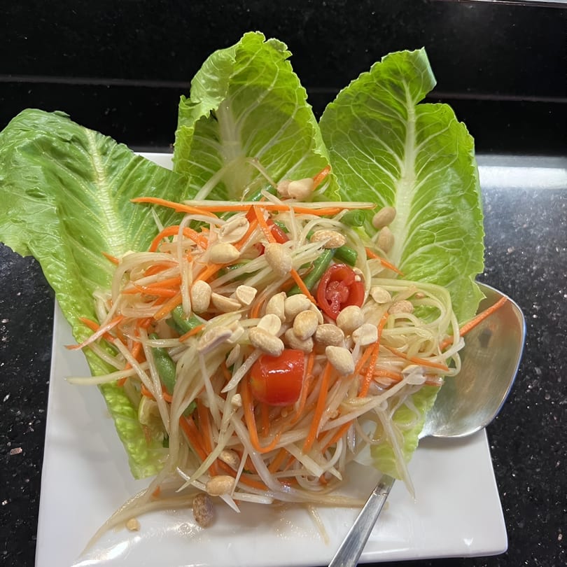 Som Tum papaya salad with peanuts, tomatoes, and green beans, served in lettuce cups.