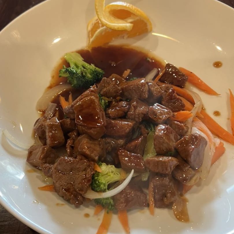Kenzo Thai & Sushi's beef dish with broccoli, carrots, onions, and a citrus garnish.