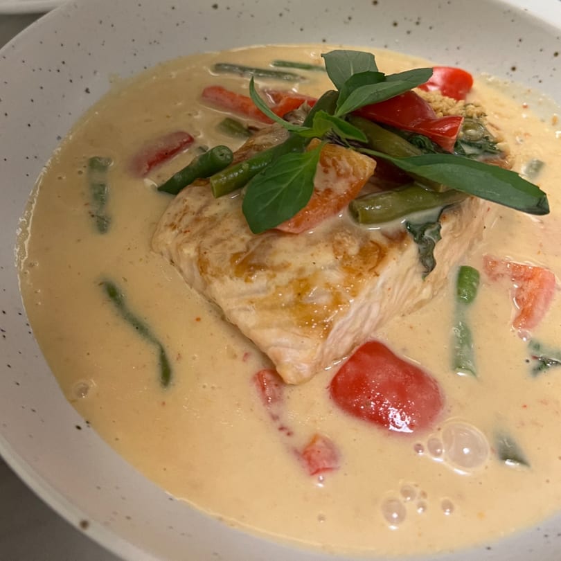 Pan-seared salmon in a creamy sauce with green beans, red bell peppers, and basil.