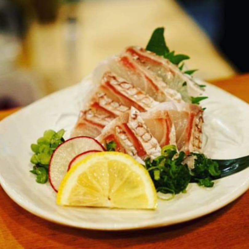 Platter of Kenzo Thai & Sushi sashimi, garnished with lemon, radish, and green onions.