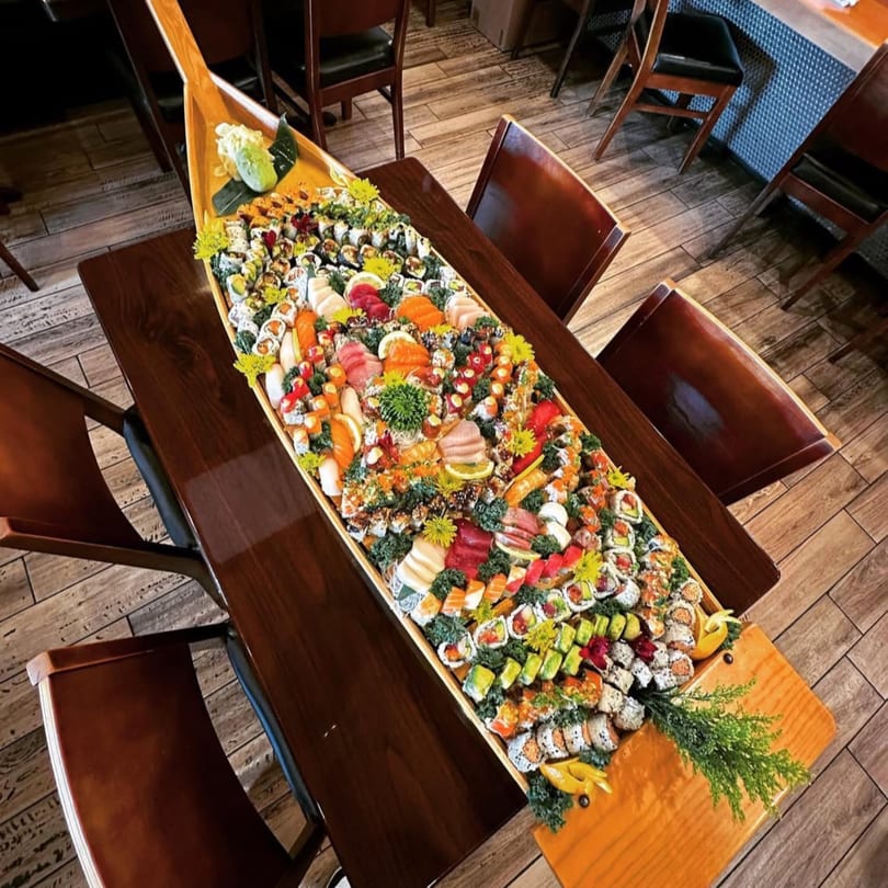 A large sushi boat from Kenzo Thai & Sushi, filled with various colorful sushi rolls and sashimi.