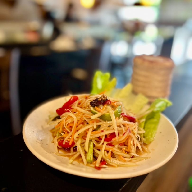 A plate of Kenzo Thai & Sushi's papaya salad with tomatoes, lime, and lettuce.