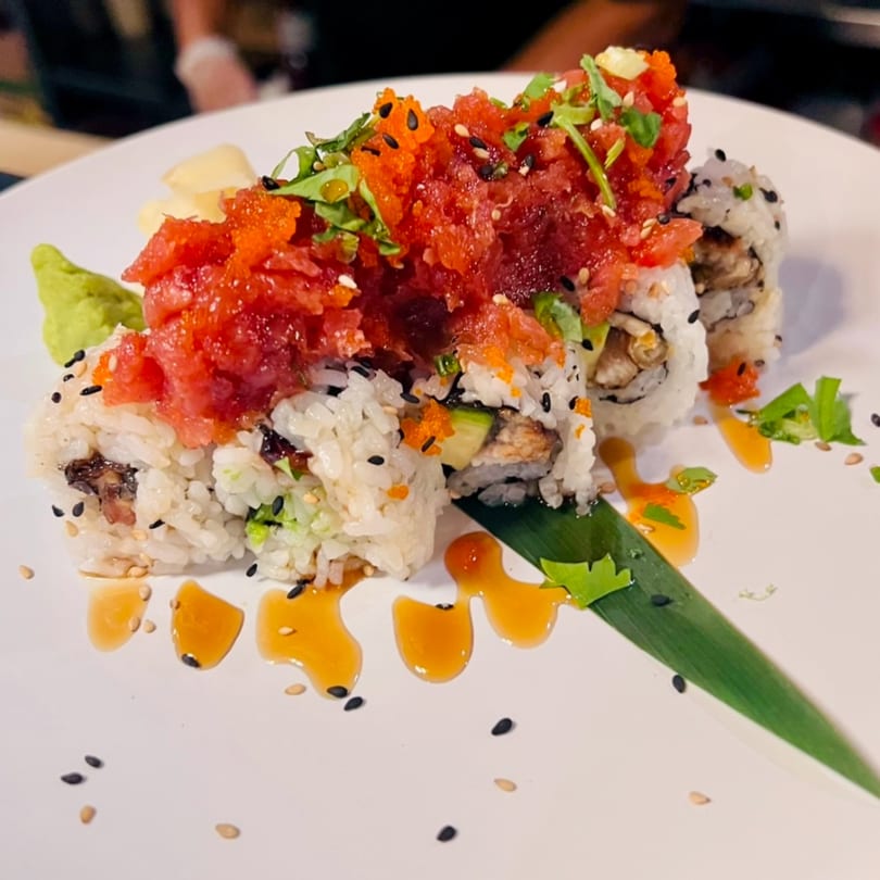 Kenzo Thai & Sushi's sushi roll topped with red tuna, orange roe, and green garnish, drizzled with sauce.